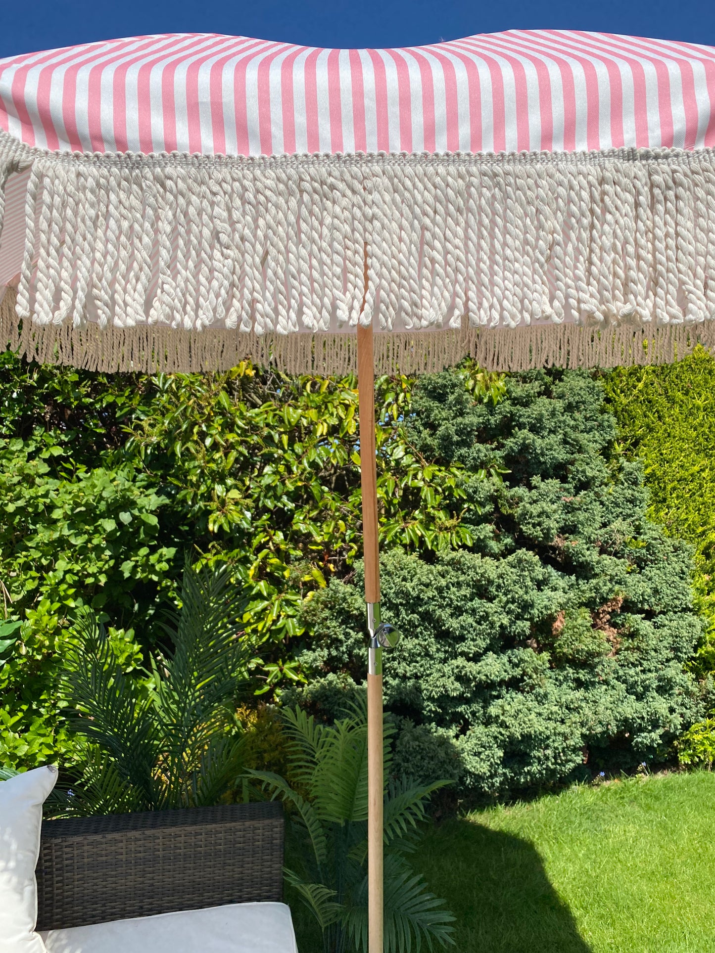 Close up image pint and white striped parasol with fringe tassel details