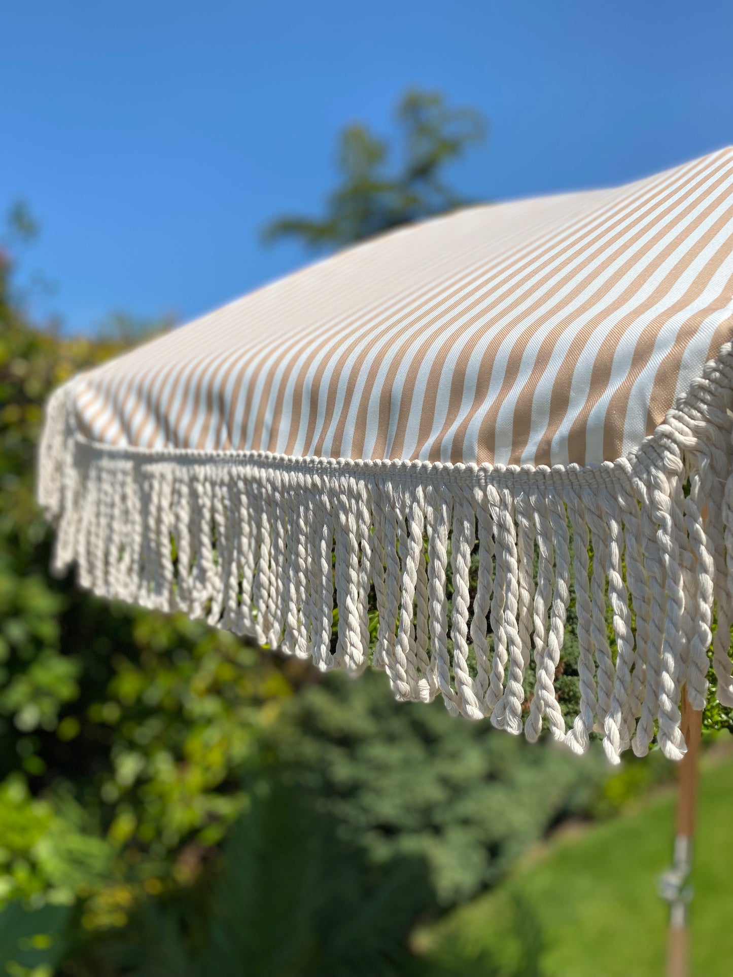 beige and white striped parasol with fringe detail